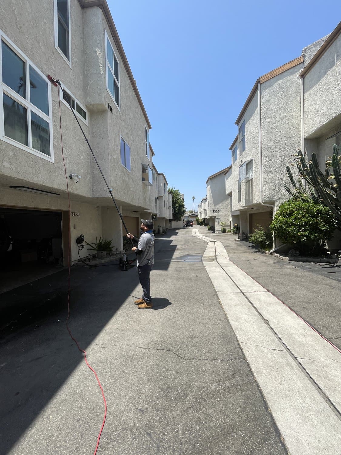 Squeegee Crew cleaning apartment windows with a water-fed pole in the 805